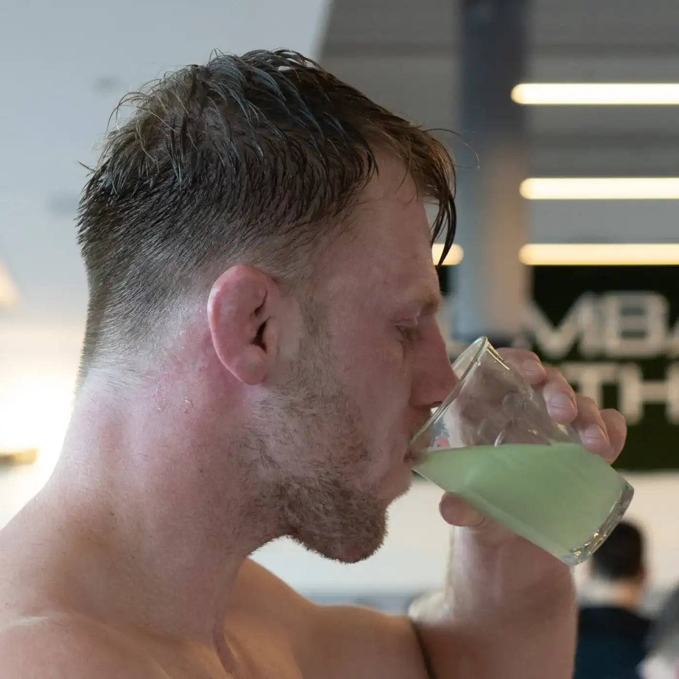 Sporter drinkt glas groene elektrolyten drank voor herstel na training