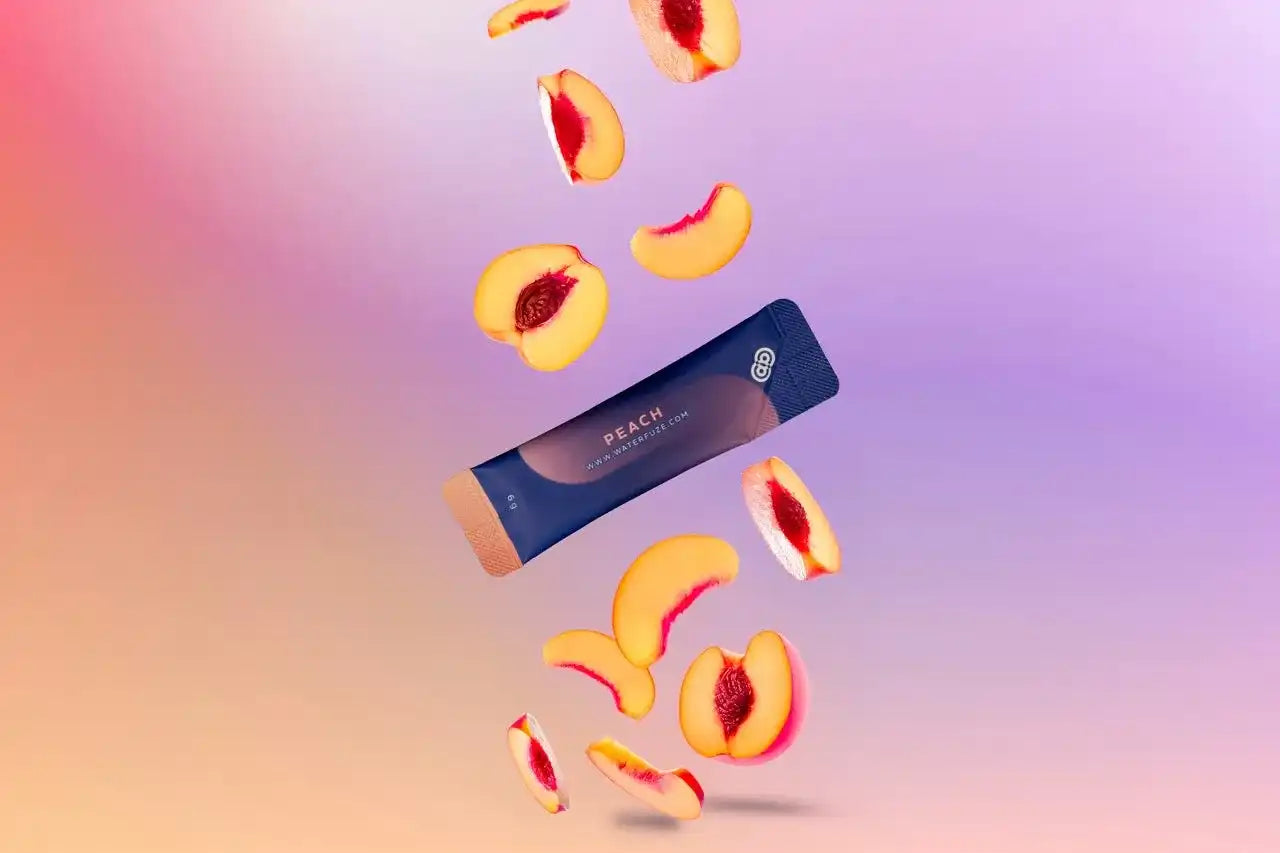 Peach elektrolyten sachet van Waterfuze omringd door zwevende verse perzikschijfjes op een kleurrijke achtergrond